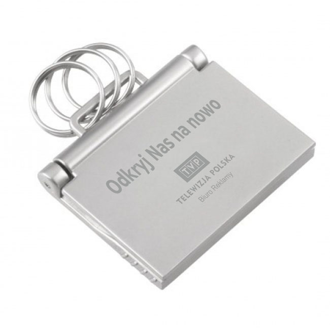 METALOWY BRELOK NA KLUCZE PRZYPOMINAJĄCY KSZTAŁTEM NOTEBOOK Z GRAWEREM DLA TVP WYGLĄDA NAPRAWDĘ ELEGANCKO